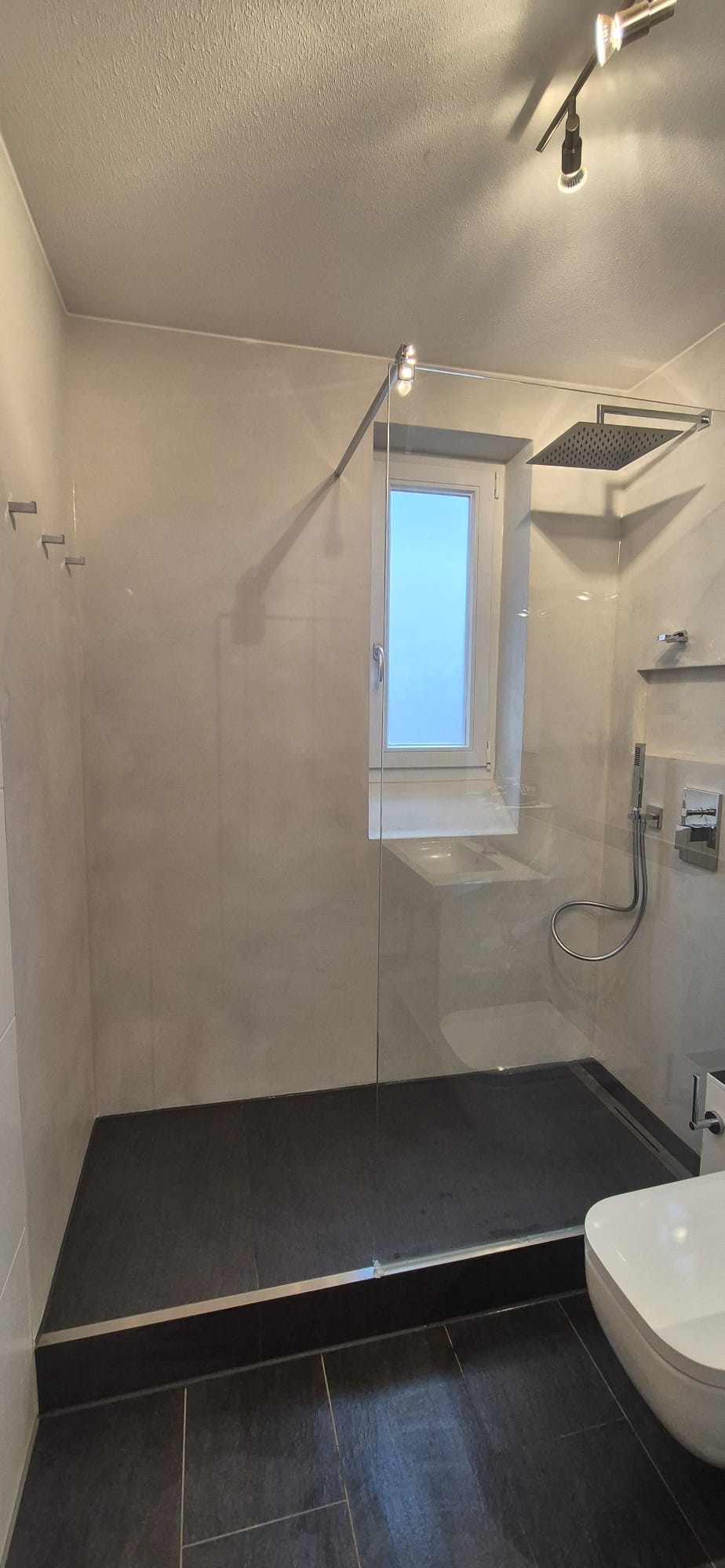 Moderne Glasdusche mit Regendusche, Fenster und heller Fliesengestaltung in einem sanierten Badezimmer in München