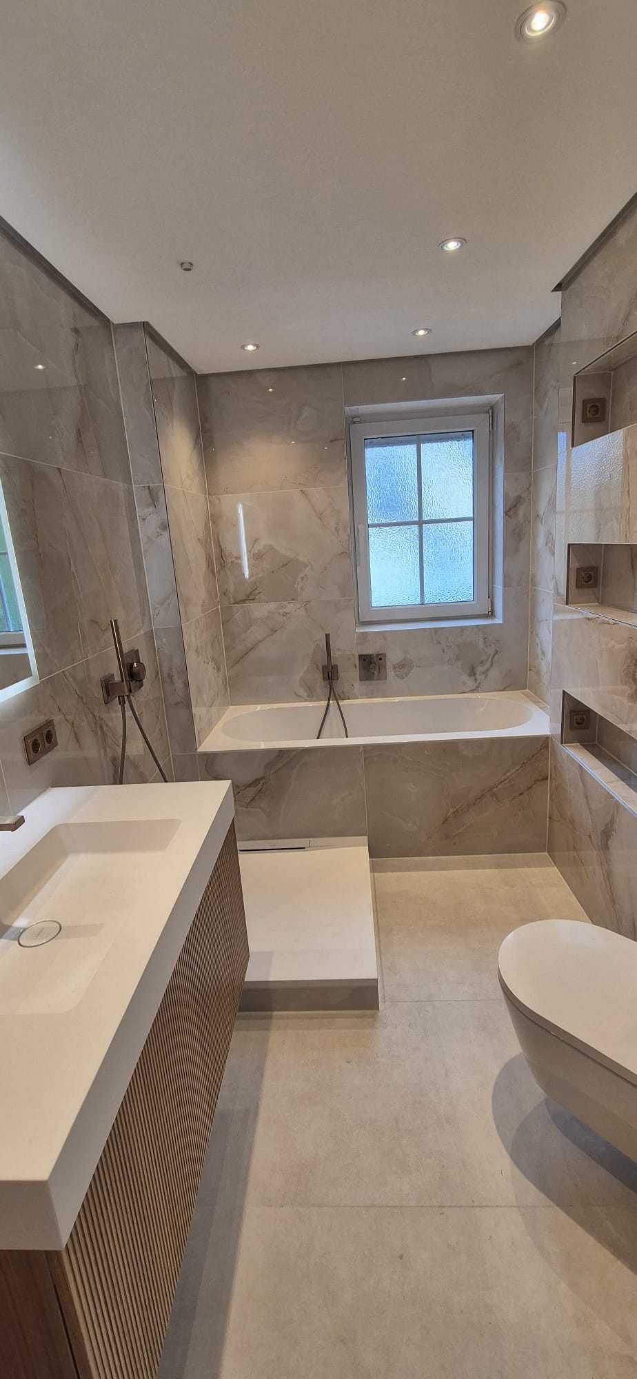 Hochwertig saniertes Badezimmer mit Badewanne, Waschtisch und großformatigen Fliesen in München