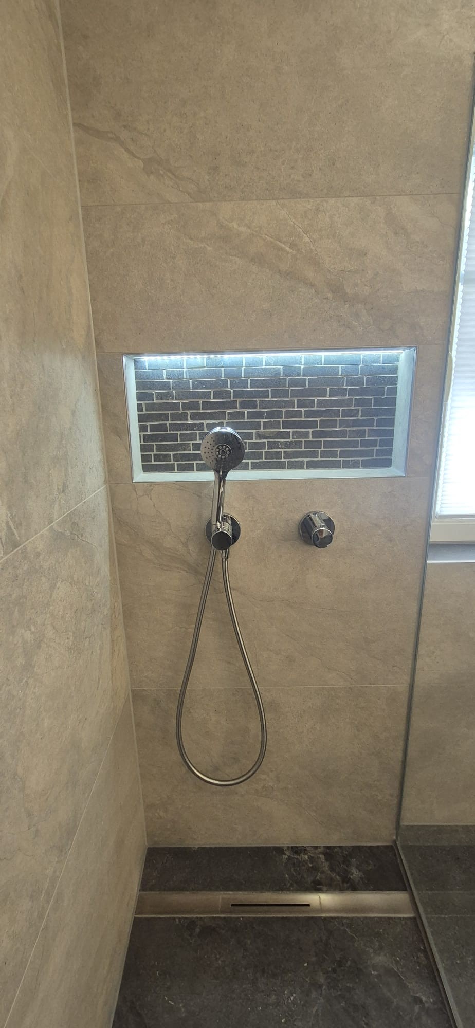 Detailansicht einer bodengleichen Dusche mit beleuchteter Wandnische und modernen Fliesen in München