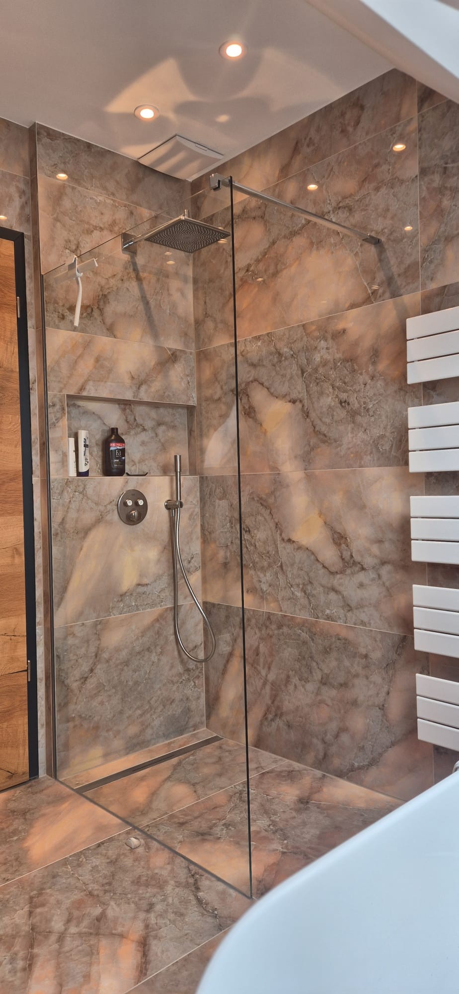 Moderne Glasdusche mit Regendusche und integrierter Wandnische in einem hochwertig sanierten Badezimmer in München