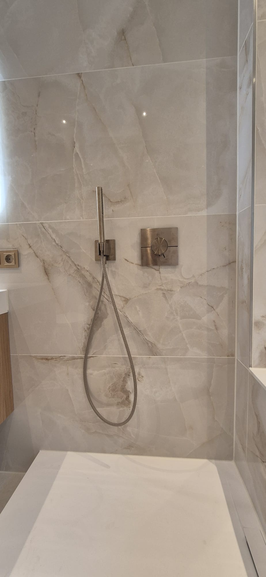 Detailansicht einer modernen Dusche mit Duscharmatur und großformatigen Fliesen in heller Steinoptik in München